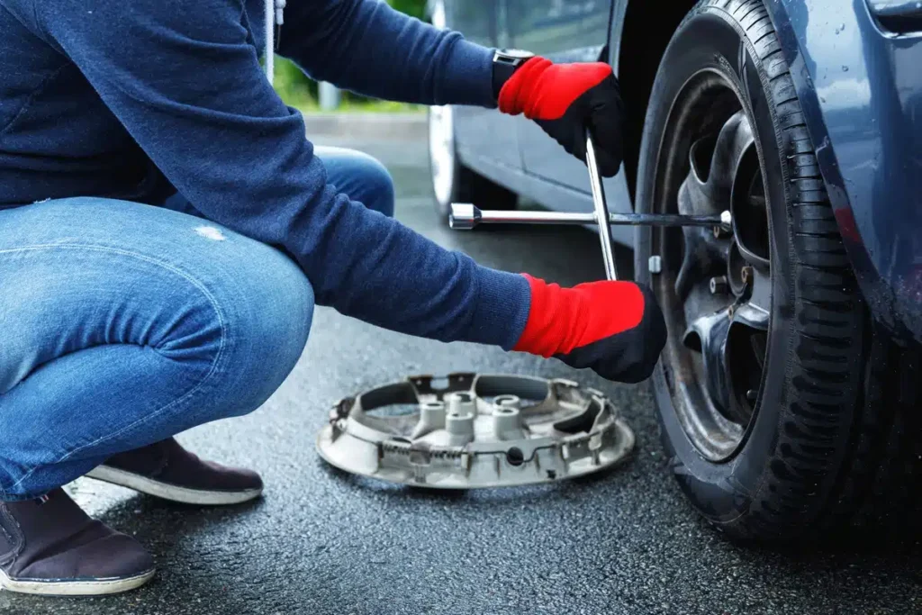 How much is it to change a tire: person replacing a flat tire on the side of the road